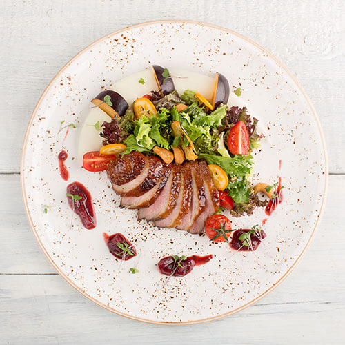 Roasted duck on a plate with side salad